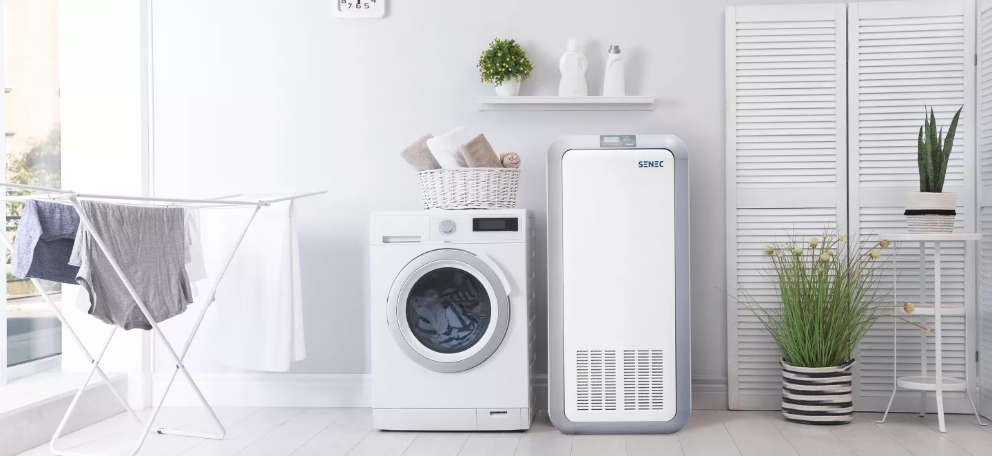 SENEC.Home Stromspeicher steht in Waschraum mit Waschmaschine und Wäscheständer