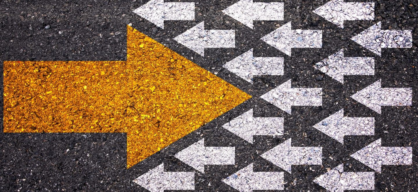 Viele kleine weiße Pfeile laufen von rechts nach links. Ein großer goldener Pfeil läuft den kleinen weißen Pfeilen entgegen und durchbricht sie. Das symbolisiert das Umdenken von disruptiven Prozessen und Technologien.