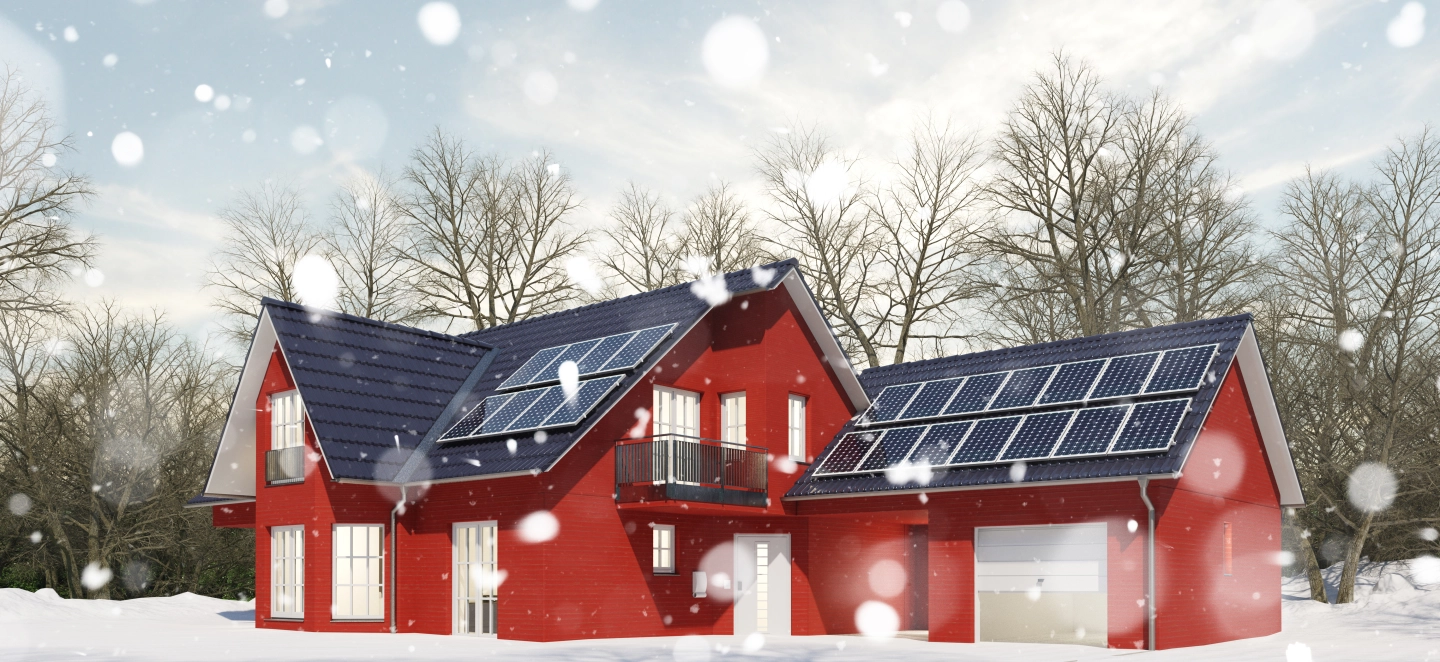 Ein Haus im Winter bei Schneefall und Kälte mit einer Photovoltaikanlage auf dem Dach zum Heizen.