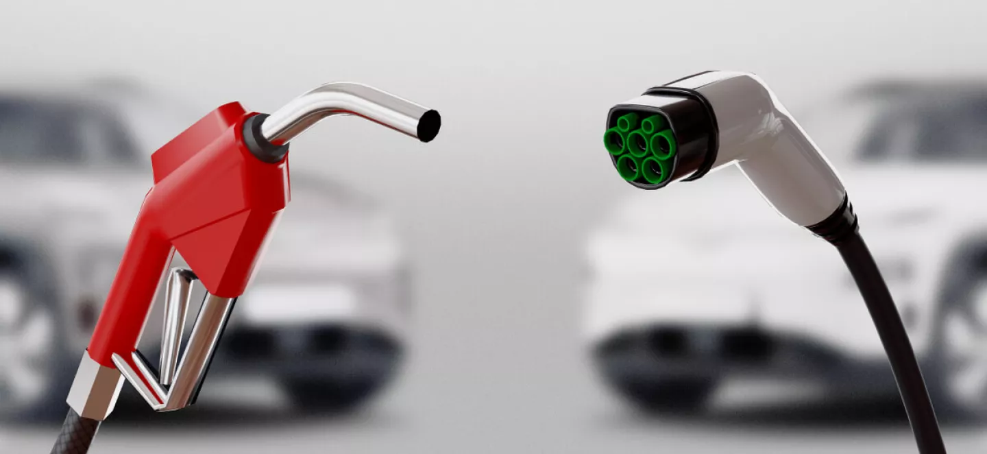 Rechts im Bild ist eine Ladepistole für ein Elektroauto. Links im Bild ist eine rote Zapfpistole für einen Benziner. 