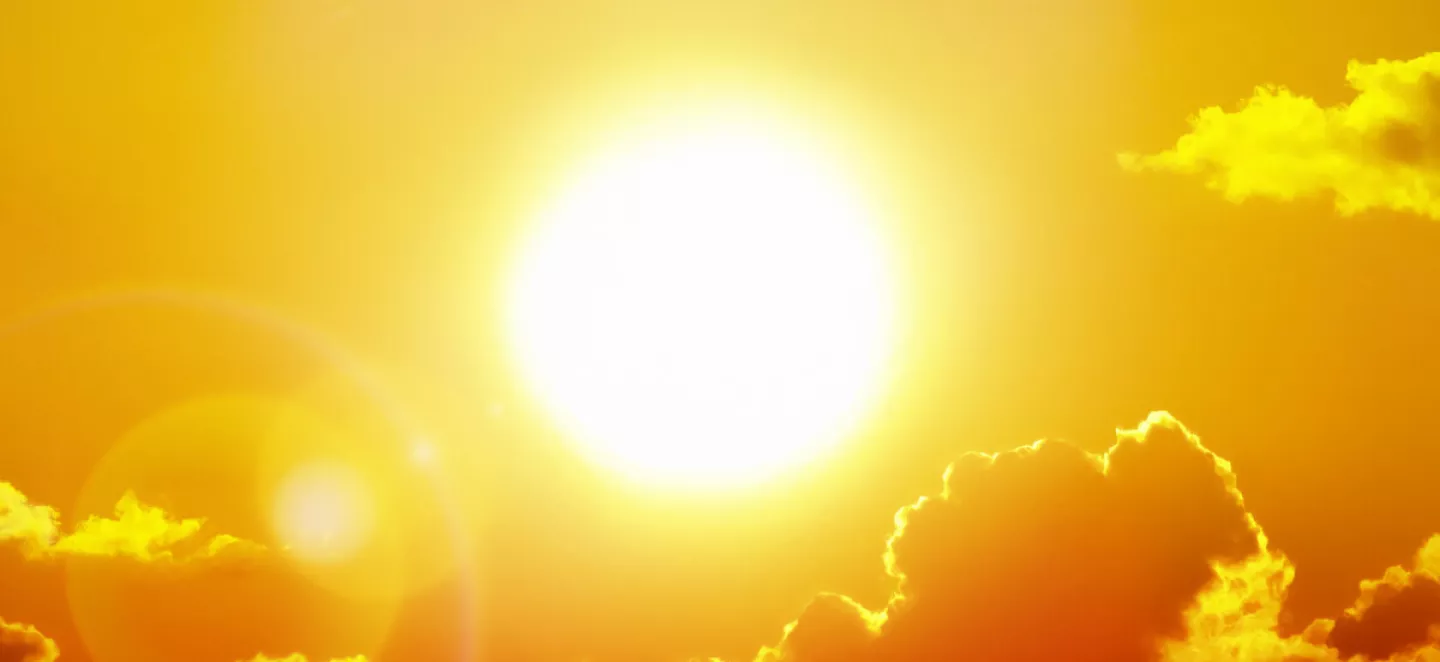 Die schöne gelbe Sonne strahlt hinter Wolken hervor.