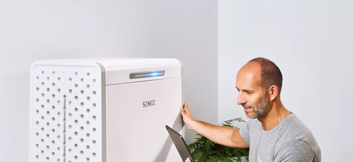 Ein Mann prüft die Leistungsdaten seines Photovoltaik-Speichers mit einem Tablet.