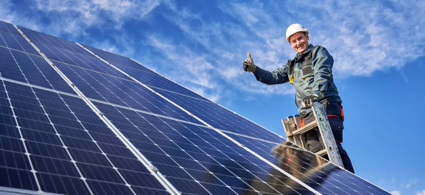 Ein Installateur begutachtet neu installierte Solarmodule und vergewissert sich von der Leistungsfähigkeit der Module.