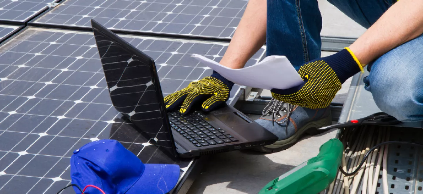 operaio su tetto con pc portatile e utensili da lavoro