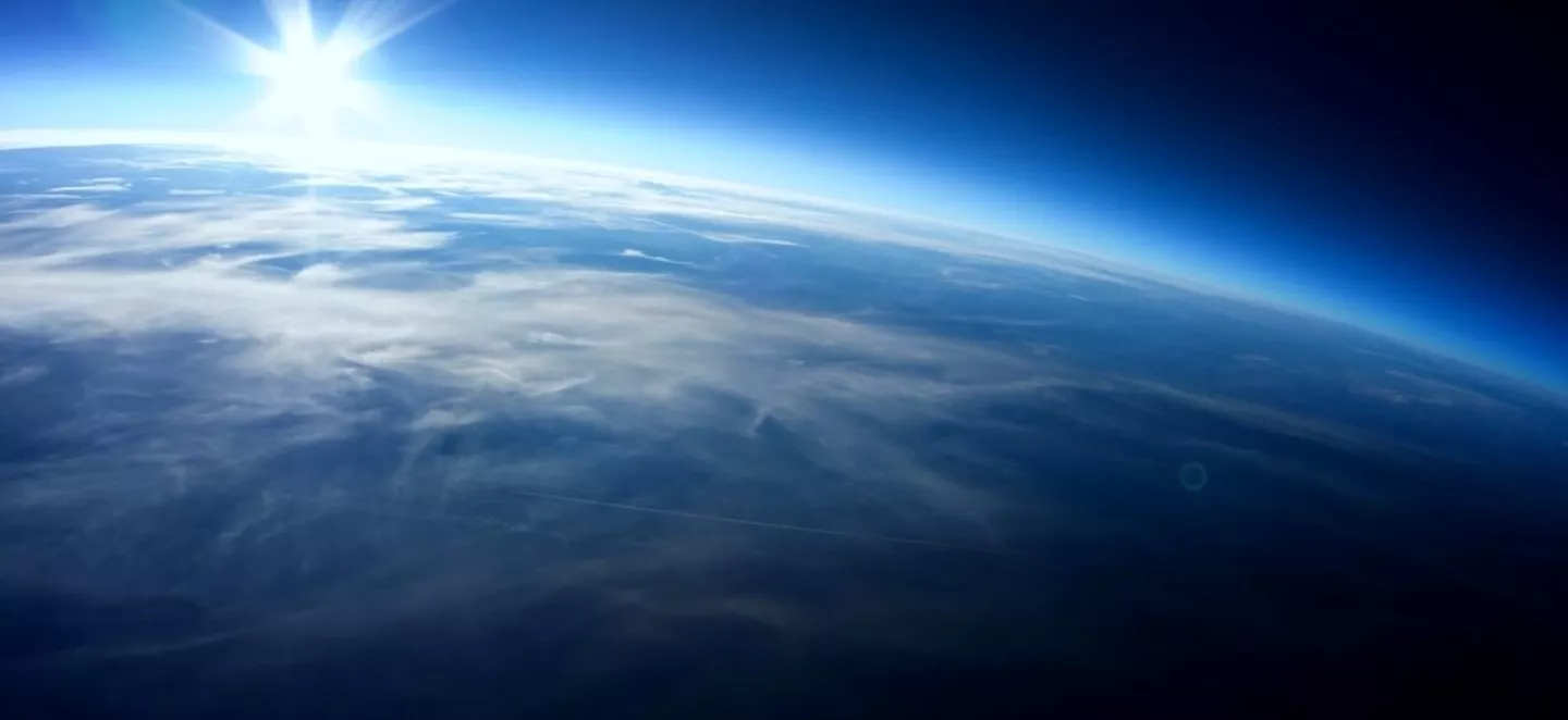 Die Erdoberfläche aus dem Weltraum mit der Sonne am Horizont.