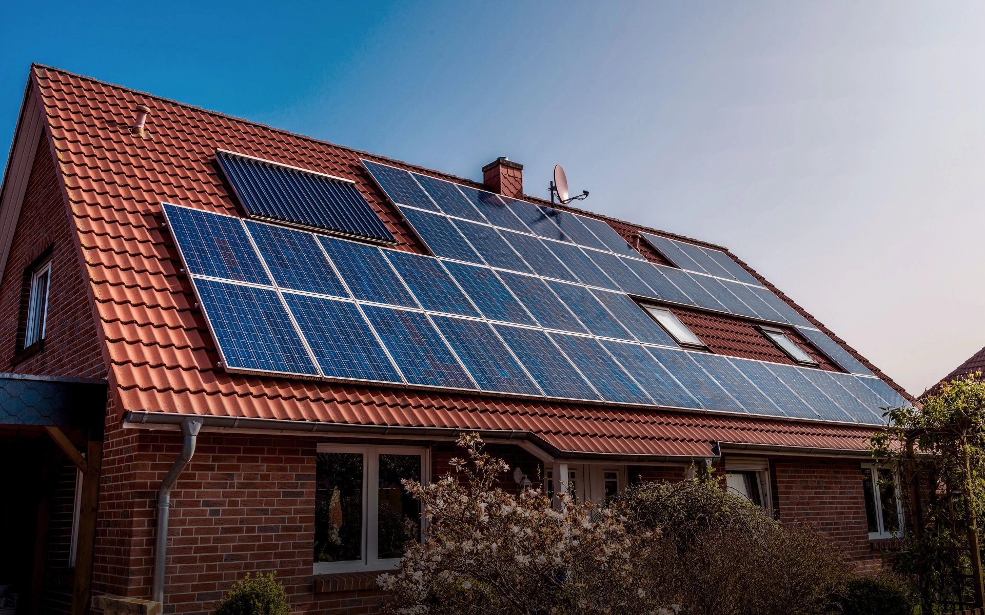 Einfamilienhaus mit Solarmodulen auf dem Dach, aus dem Garten des Grundstücks fotografiert