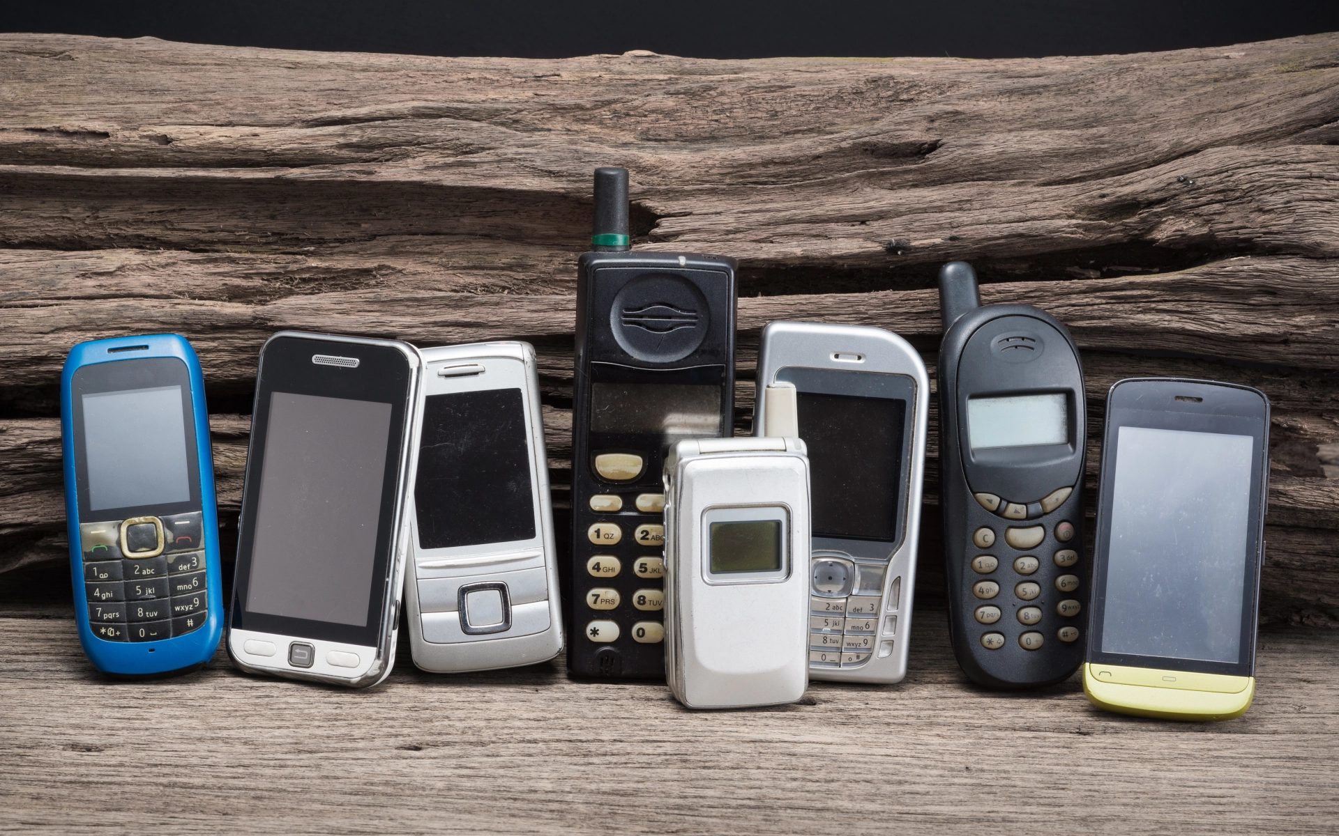 Acht Mobil-Telefone, wie sie seit den 90er-Jahren verwendet wurden. Ganz rechts im Bild ist ein Smartphone mit Touch-Display, das die Entwicklung in eine neue Richtung von Mobil-Telefonen zeigt.