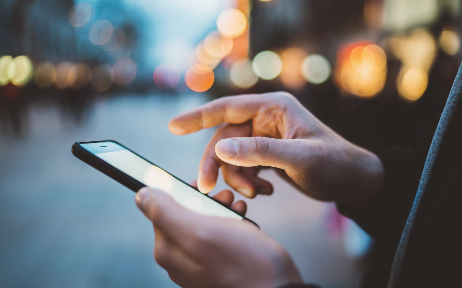 Vor einer Stadtszene sieht der Betrachter eine Hand, die ein Smartphone benutzt. Die tägliche Szene zeigt, wie wenig Angst Nutzer haben, dass das Handy plötzlich anfängt zu brennen.
