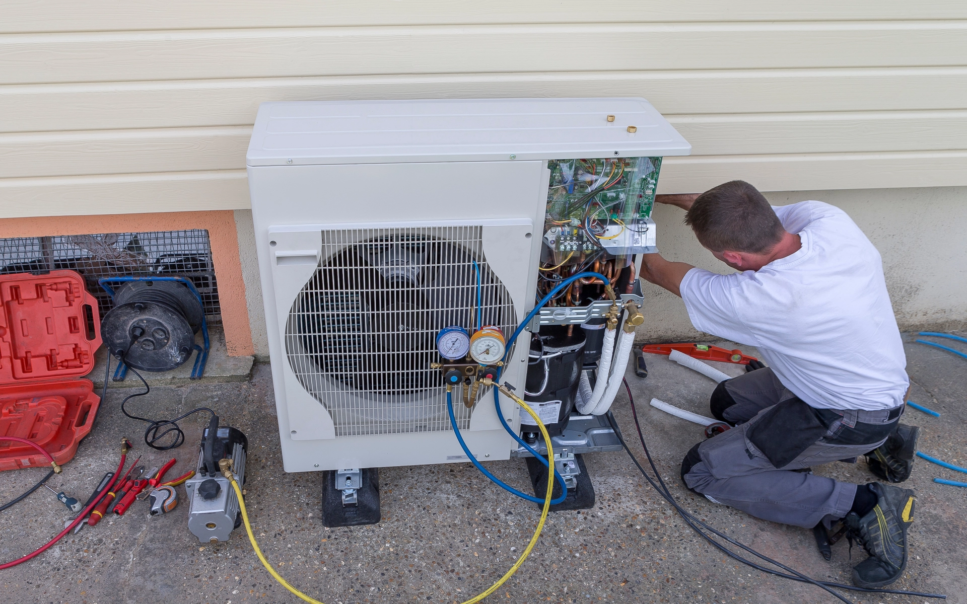 Ein Klempner installiert eine Umwälzwärmepumpe an einem Haus.
