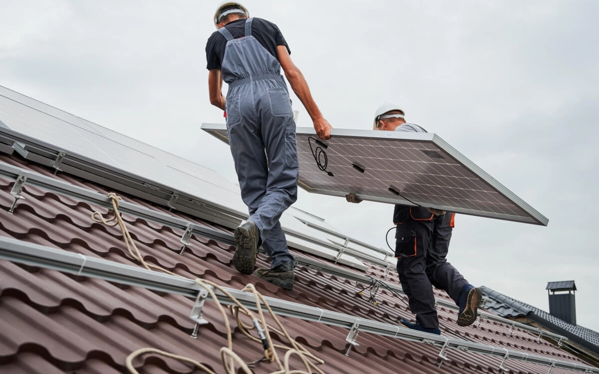 Zwei Monteure installieren ein Solar-Modul auf einem Dach.