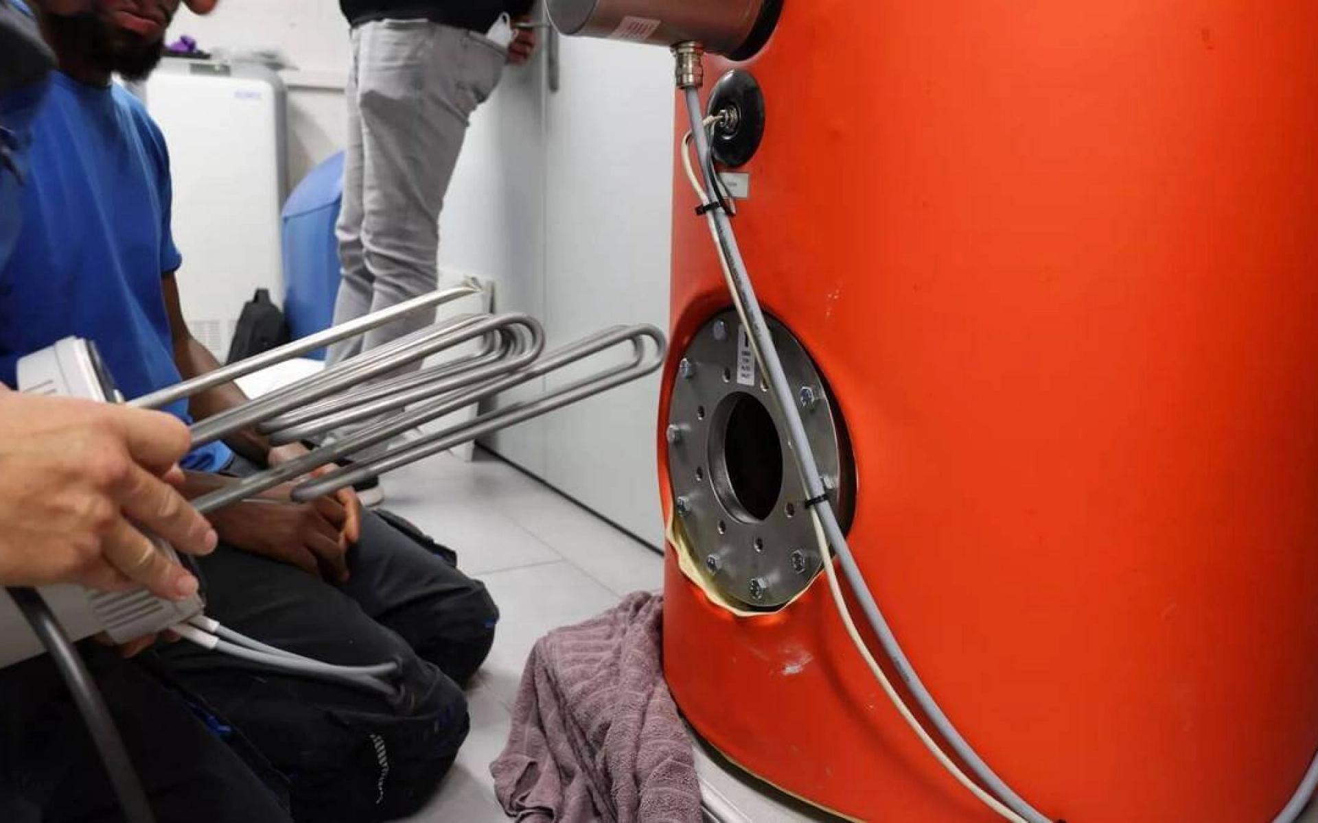 Foto von einem Installateur, der einen Heizstab in einen Wassertank einbaut.