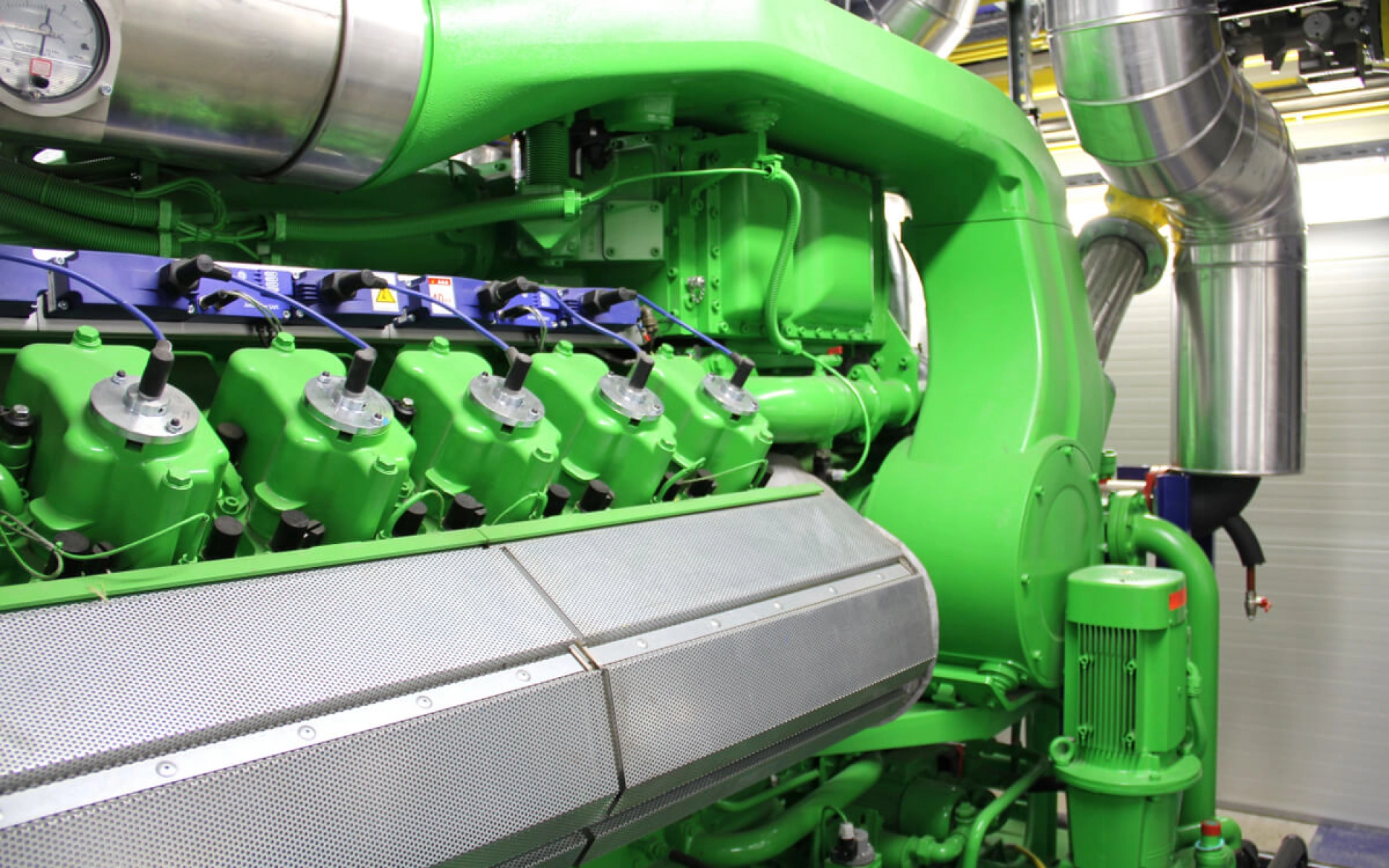 Der Motorblock eines Heizkraftwerks mit Ableitungsrohren im Hintergrund.