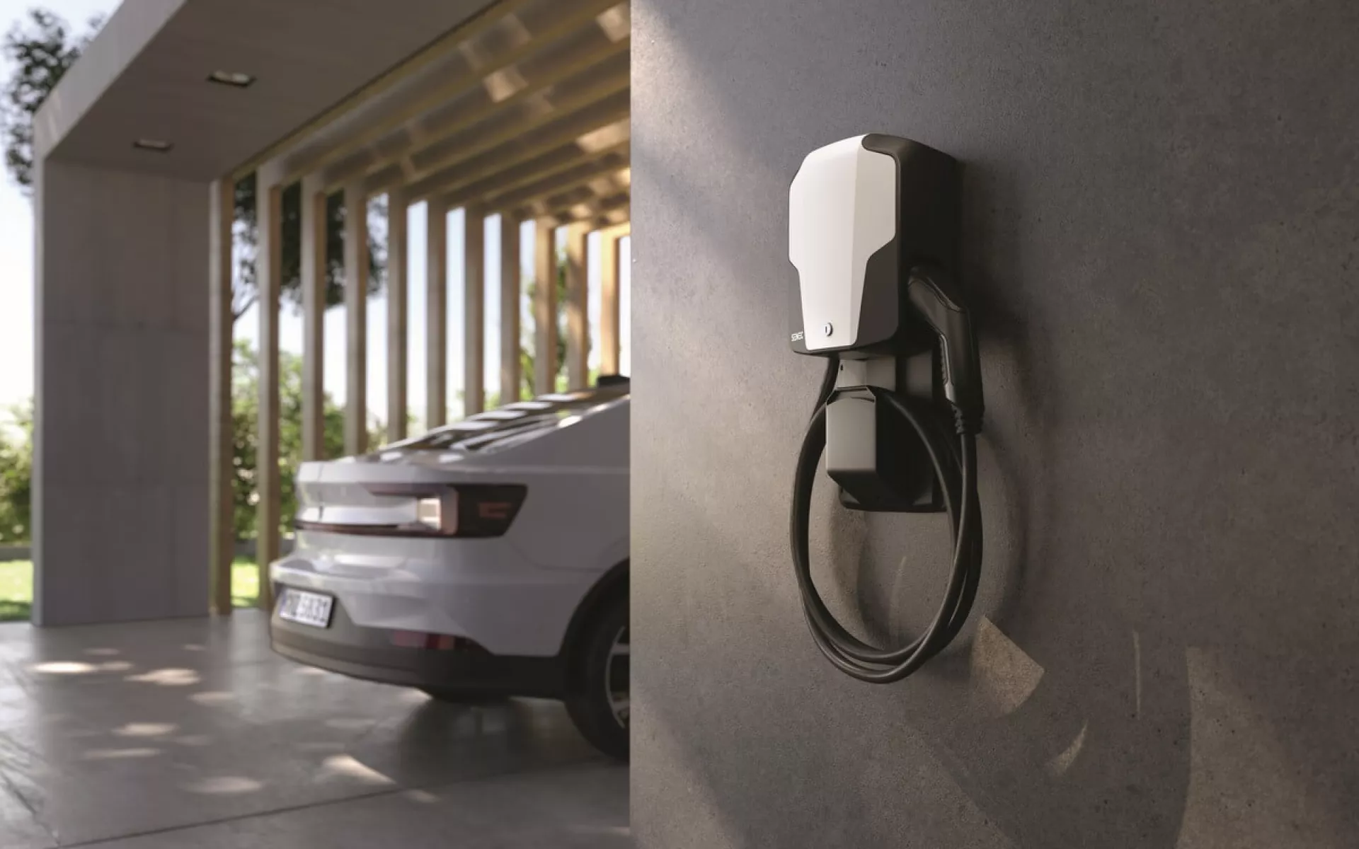 Eine Wallbox hängt an der Wand und im Hintergrund steht ein Elektroauto.