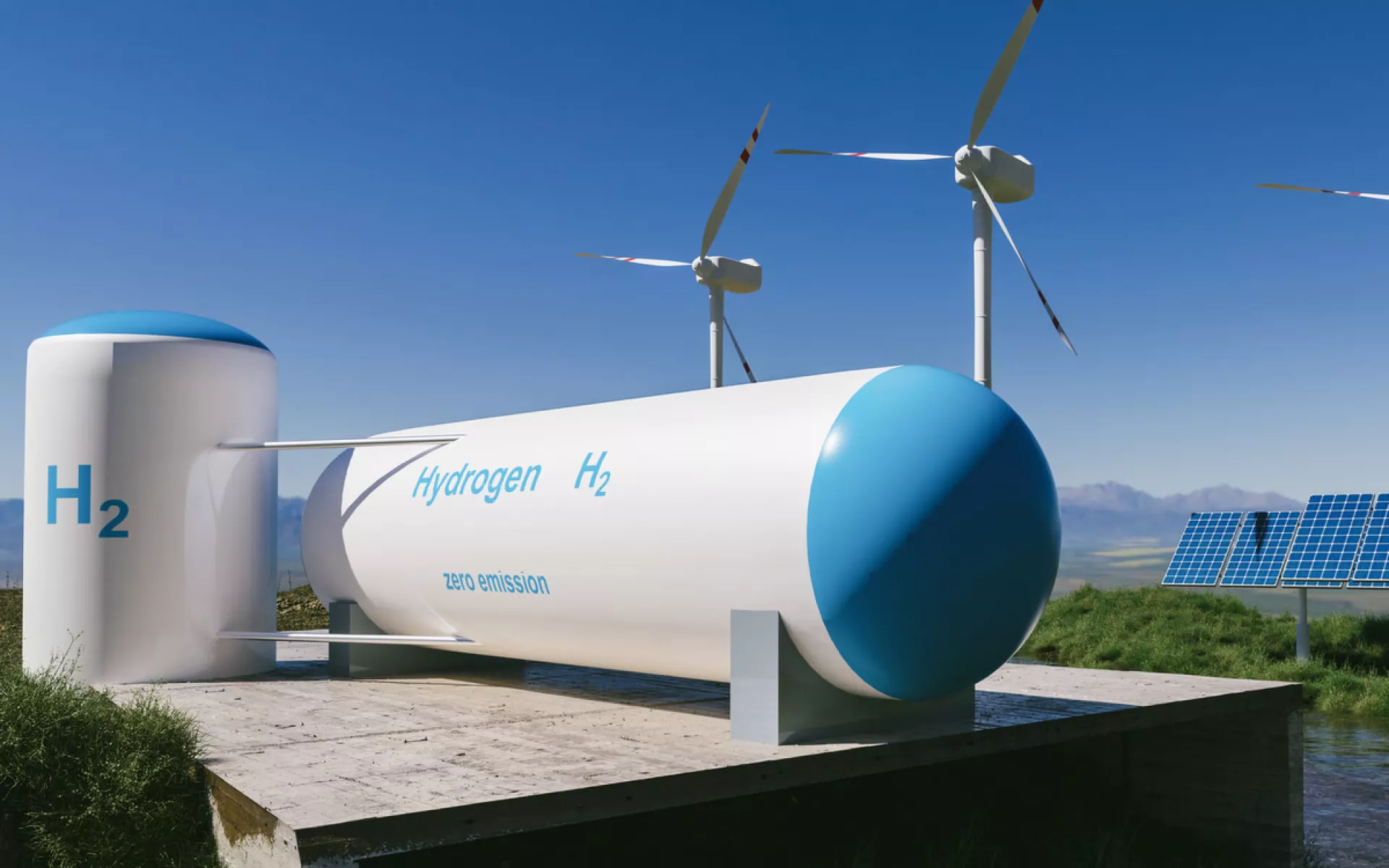 Eine Wasserstoff-Speicher unter freiem Himmel mit Windkrafträdern und Solarmodulen im Hintergrund. 