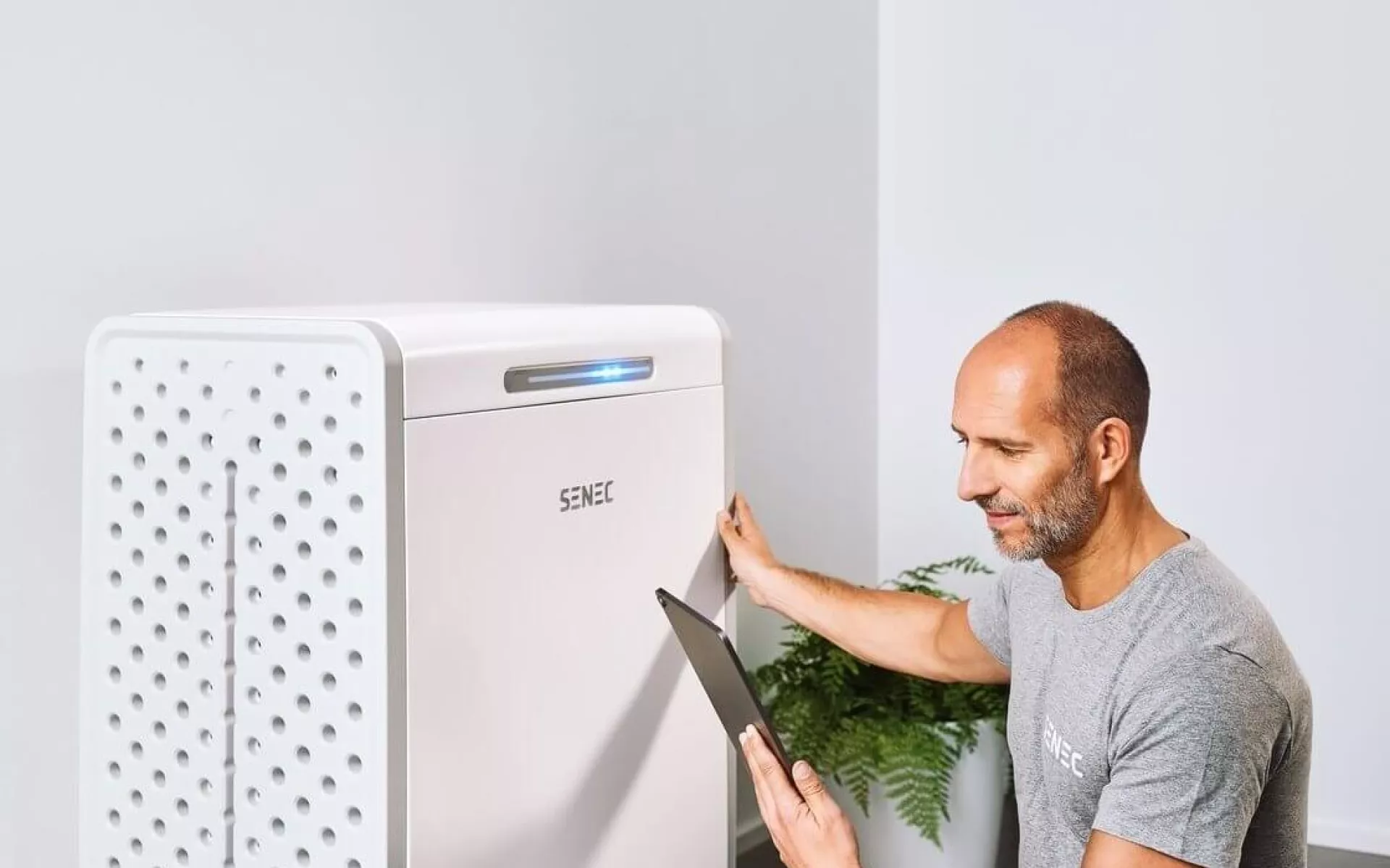 Ein Installateur kontrolliert die Dimensionierung eines Photovoltaik-Speichers mit seinem Tablet.