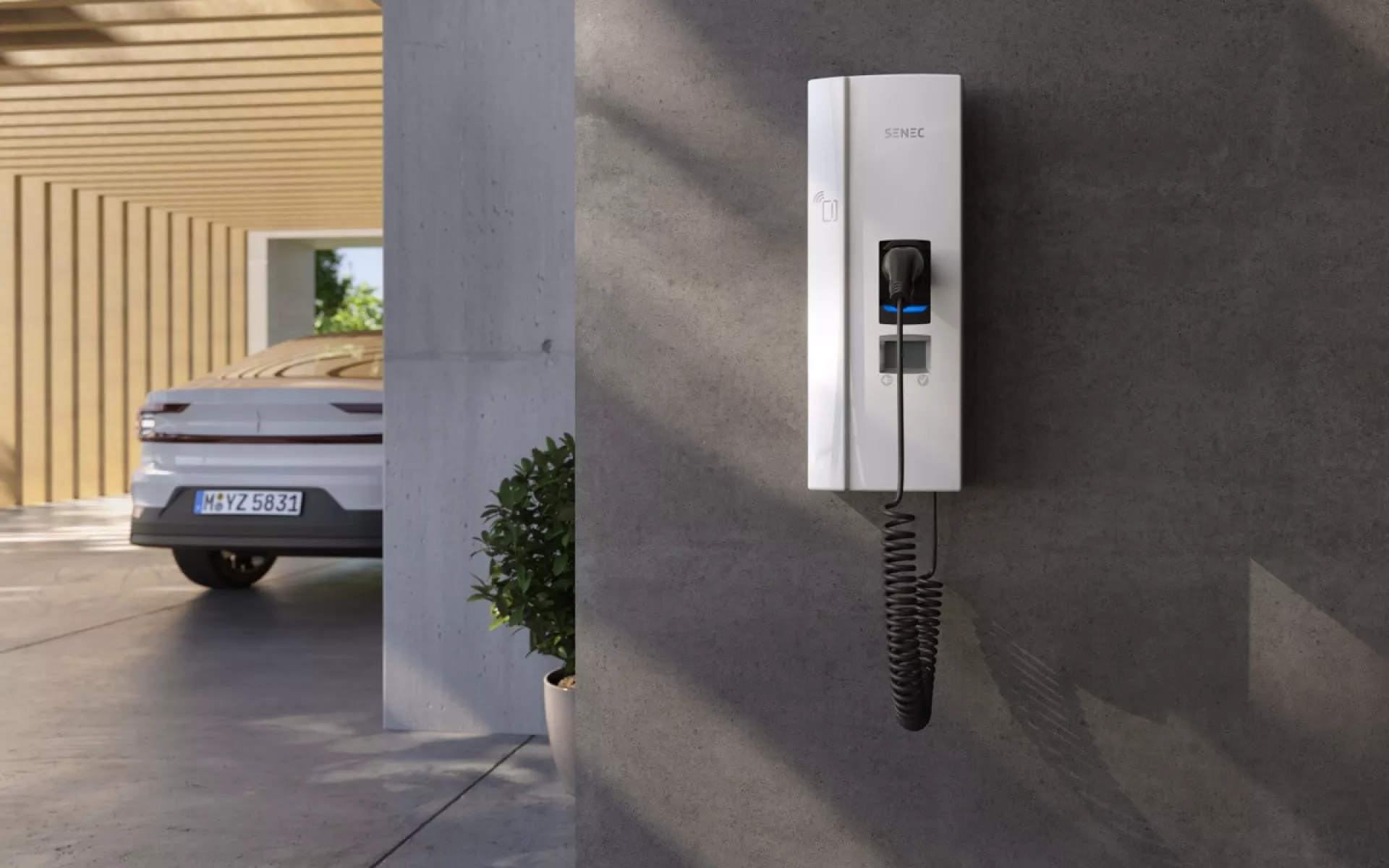 Wallbox hängt nach der Anmeldung im Carport bereit zum Laden des E-Autos, das im Hintergrund parkt.
