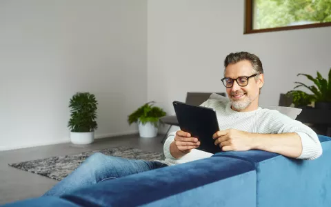 Mann mit Tablet auf Couch