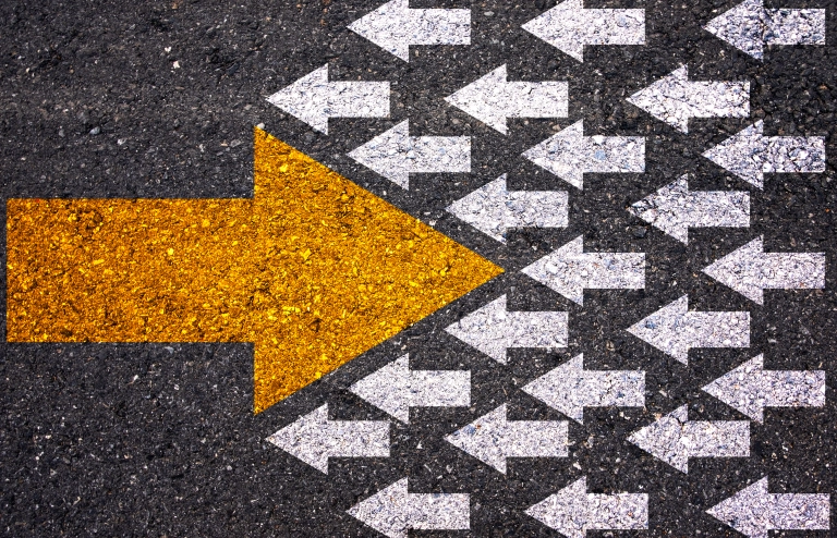 Viele kleine weiße Pfeile laufen von rechts nach links. Ein großer goldener Pfeil läuft den kleinen weißen Pfeilen entgegen und durchbricht sie. Das symbolisiert das Umdenken von disruptiven Prozessen und Technologien.