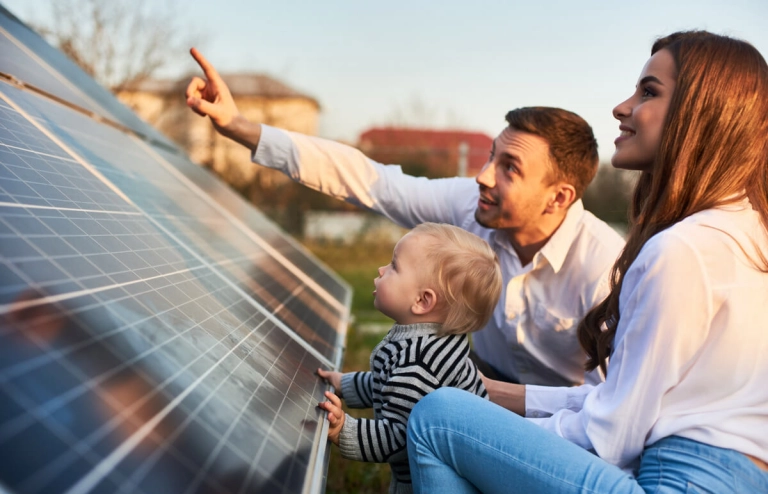 Ein junger Vater zeigt seinem Kind und seiner Frau eine Solarstrom-Anlage und erklärt die Speicherung.