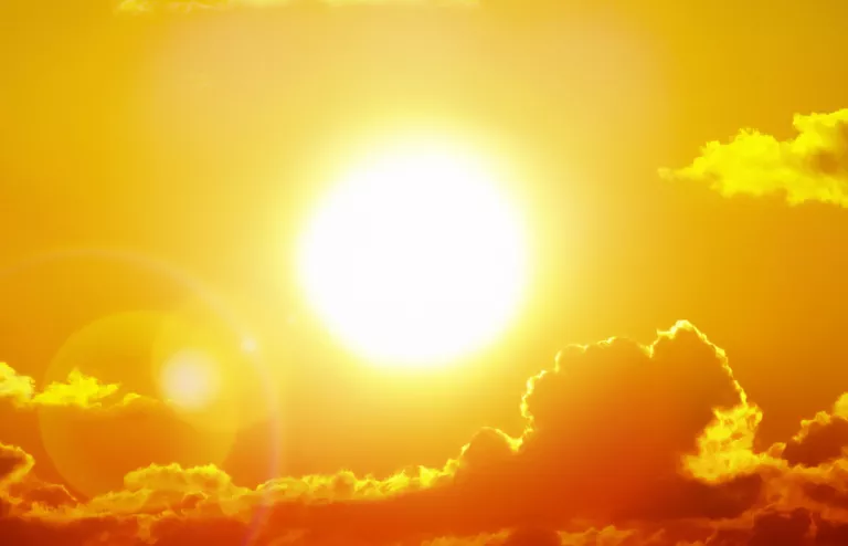 Die schöne gelbe Sonne strahlt hinter Wolken hervor.