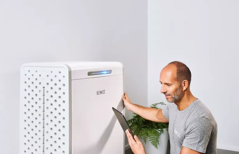 Ein Mann prüft die Leistungsdaten seines Photovoltaik-Speichers mit einem Tablet.