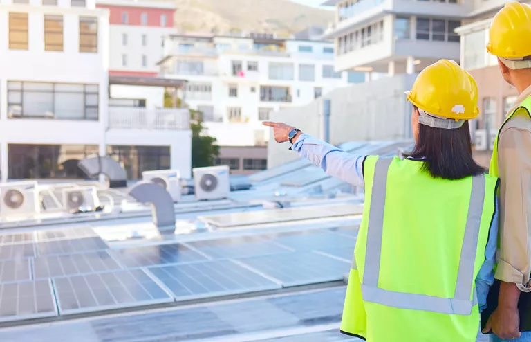 architetto ed ingegnere che osservano un impianto fotovoltaico sul tetto di un'azienda