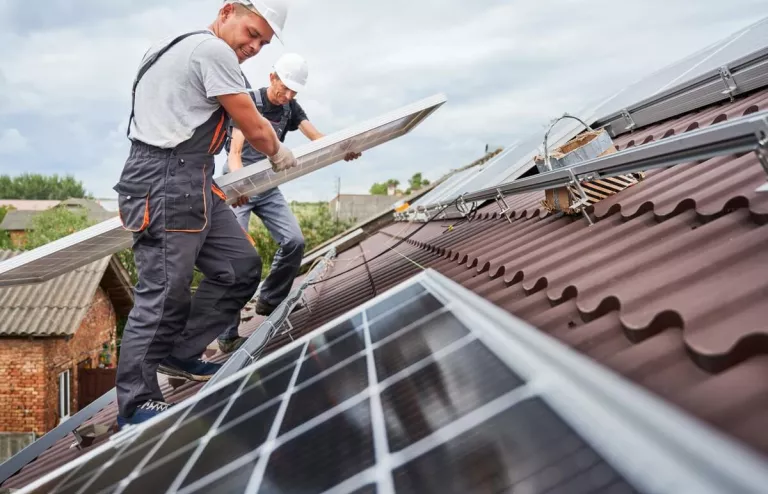 Zwei Solar-Installateure bauen PV-Module auf ein Dach.
