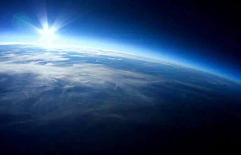 Die Erdoberfläche aus dem Weltraum mit der Sonne am Horizont.