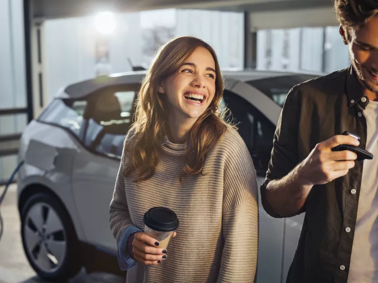 Junges Paar mit Elektroauto bei Laden in Tiefgarage