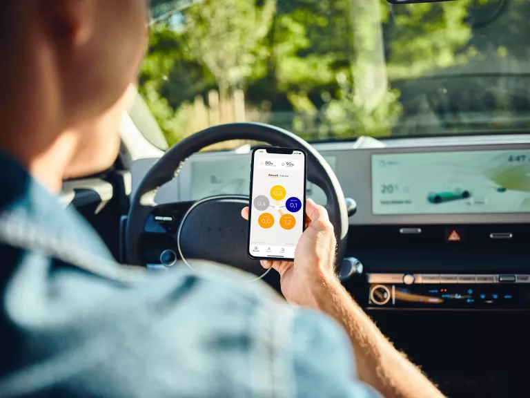 Person im E-Auto mit SENEC.App auf Smartphone
