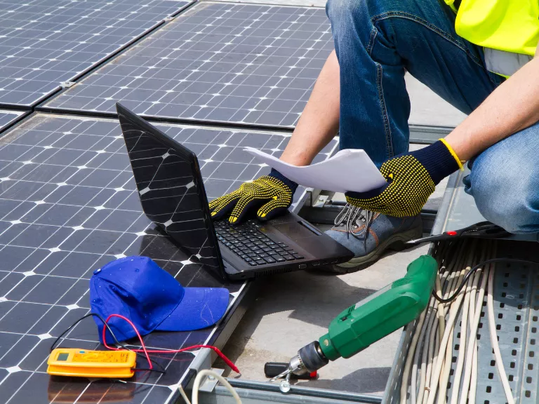 operaio su tetto con pc portatile e utensili da lavoro