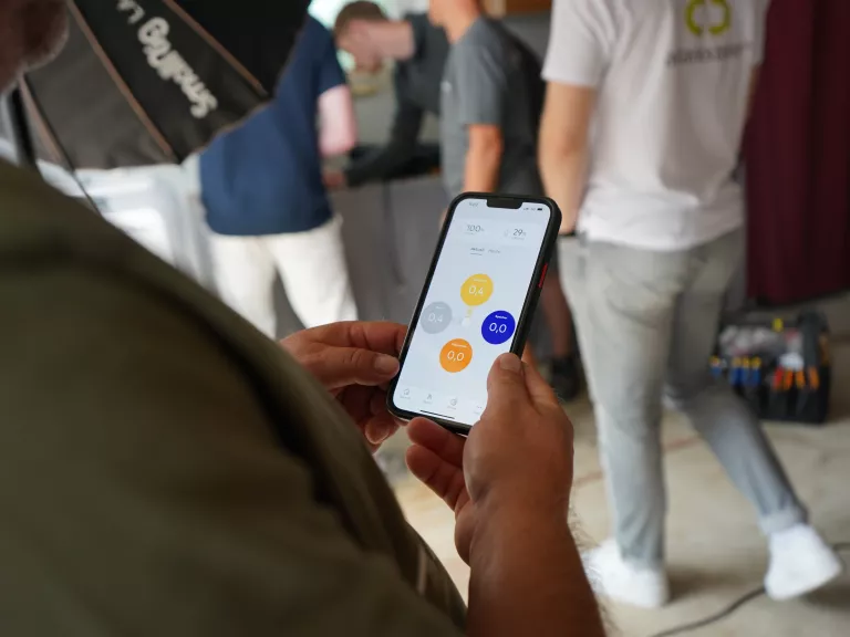 Person mit Smartphone und SENEC.App auf dem Bildschirm