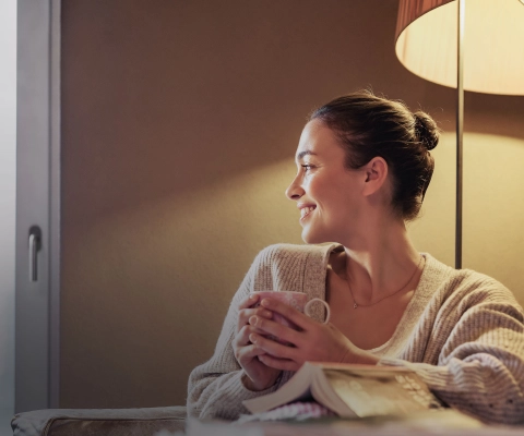 woman with teacup and warm lights behind her