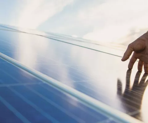 Eine Hand streicht zart über ein Solar-Panel.