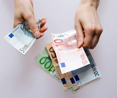 Zwei Hände zählen Geld und legen es auf den Tisch.