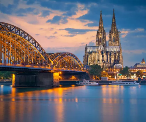 Blick auf den Dom von Köln vom Rhein aus bei Abendlicht.